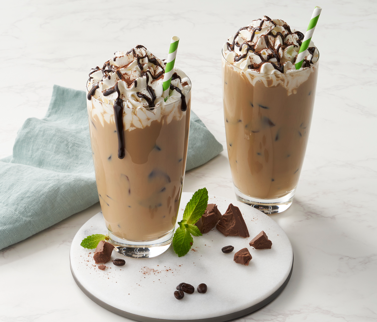 Two glasses of chocolate milkshakes on a plate