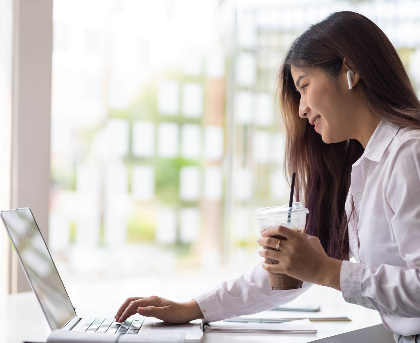 a woman sitting at a desk with a laptop and a cup of coffee